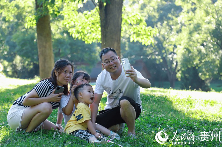 在阿哈湖公園內四口之家拍合影。人民網 顧蘭云攝