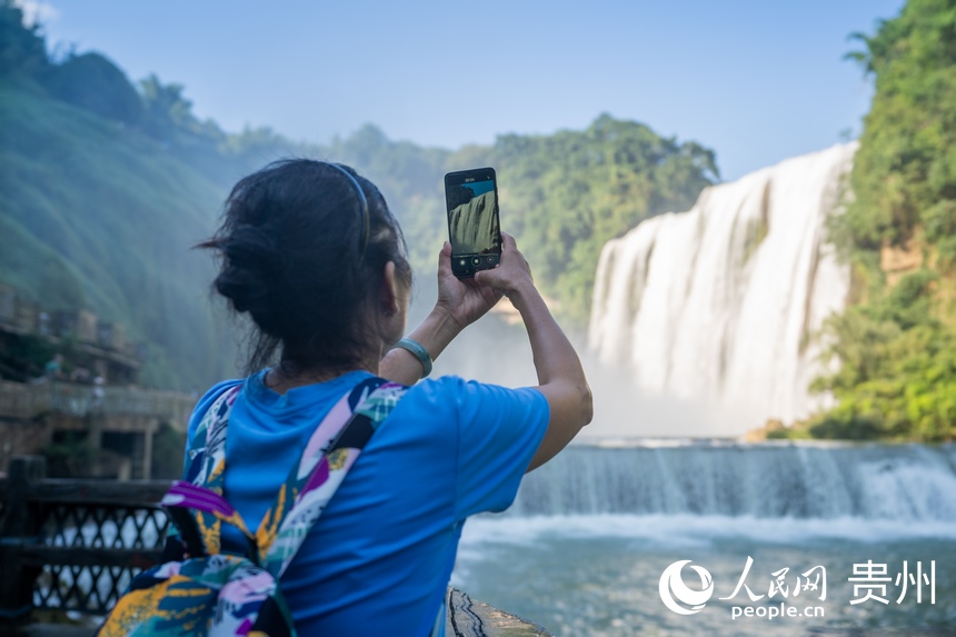 游客在黃果樹大瀑布前拍照。人民網 涂敏攝