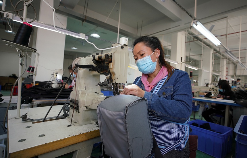 10月11日，工人在移民安置社區“幫扶車間”加工背包。
