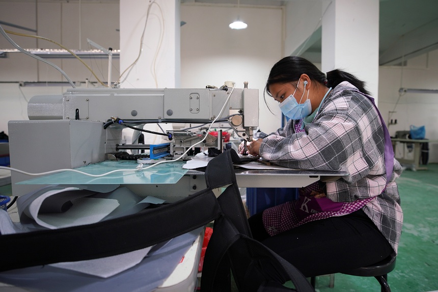 10月11日，工人在移民安置社區“幫扶車間”加工背包。