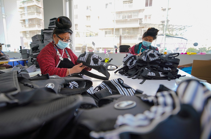 10月11日，工人在移民安置社區“幫扶車間”檢查背包成品質量。