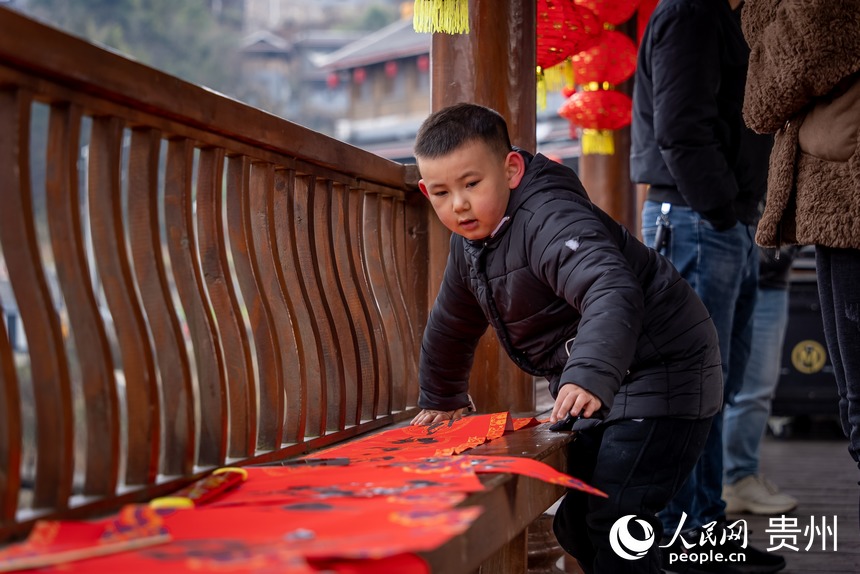 小朋友正在晾曬剛剛寫好的春聯。人民網 涂敏攝