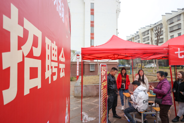 在七星關區歸化街道生態移民安置點招聘會現場 企業工作人員正在向搬遷群眾介紹薪資待遇。