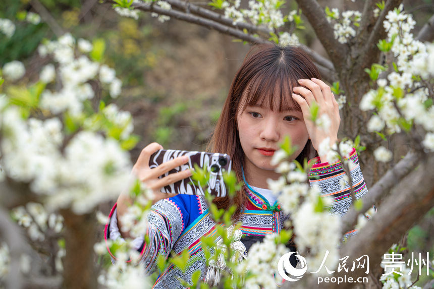 游客身著布依族服飾站在花叢里拍照。人民網 陽茜攝
