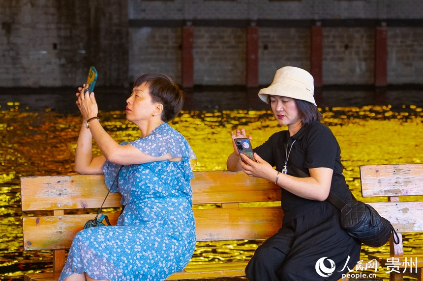 游客坐在岸邊的長椅上拍照。人民網 陽茜攝