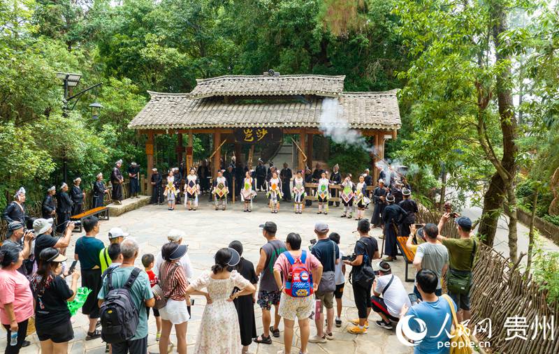 在岜沙苗寨，當地苗族同胞在寨門迎接游客。 人民網 陽茜攝