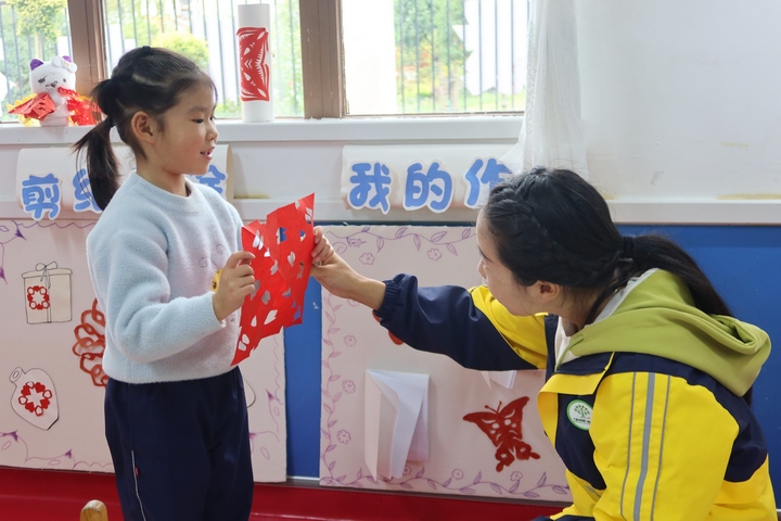 老師正在夸贊學生的剪紙作品。楊锏攝