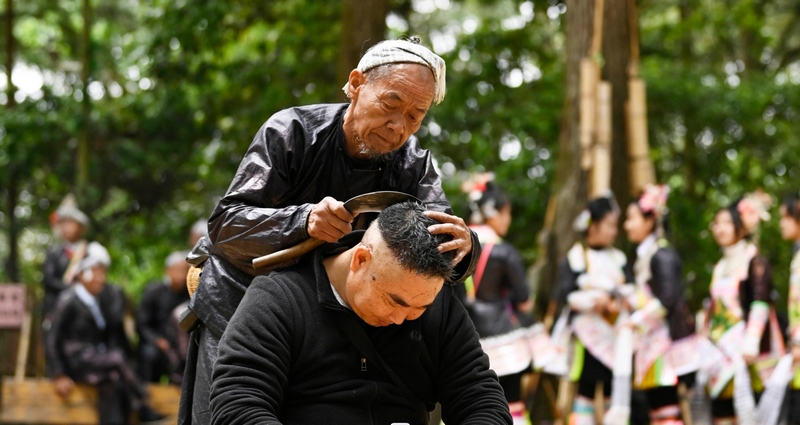 2024年5月1日，一名游客在貴州省黔從江縣丙妹鎮岜沙苗寨景區體驗鐮刀剃頭。