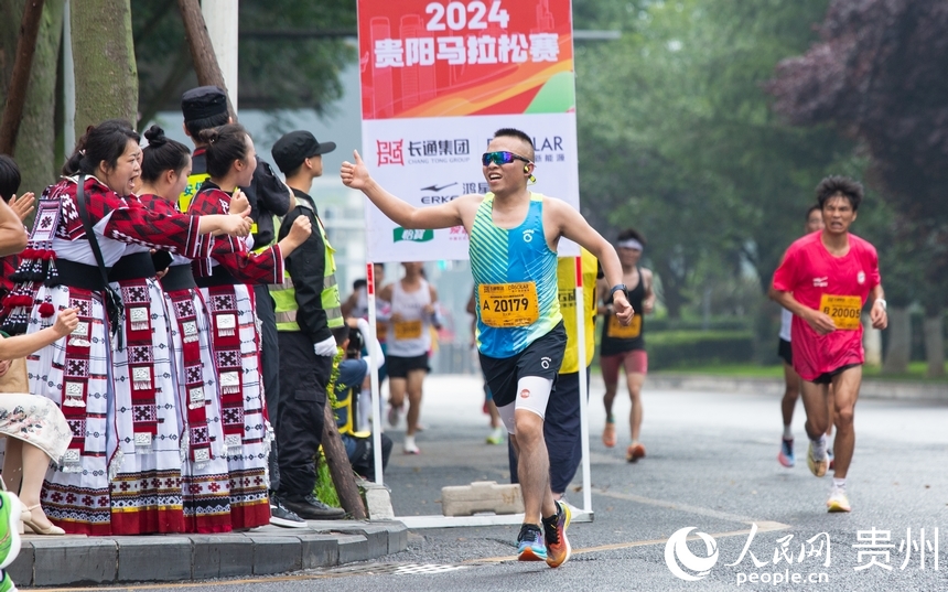 參賽選手與身著少數民族服飾的觀眾打招呼。人民網記者 高華攝