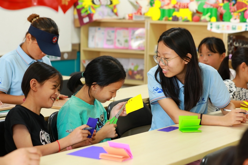 南昌大學的大學生志愿者指導孩子們做手工。
