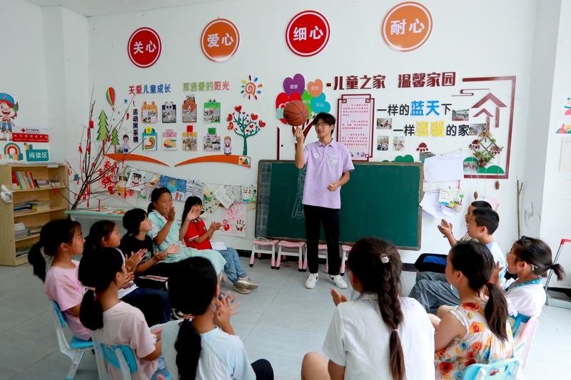 合肥工業大學社會實踐團的大學生志愿者和孩子們一起玩游戲。