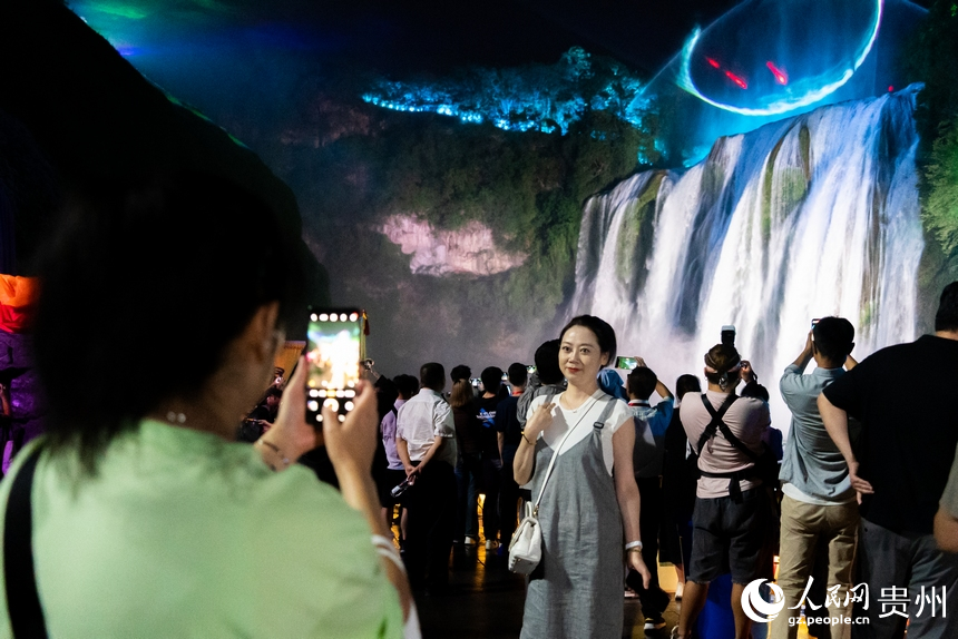 游客在夜間黃果樹瀑布前打卡拍照。人民網記者 涂敏攝