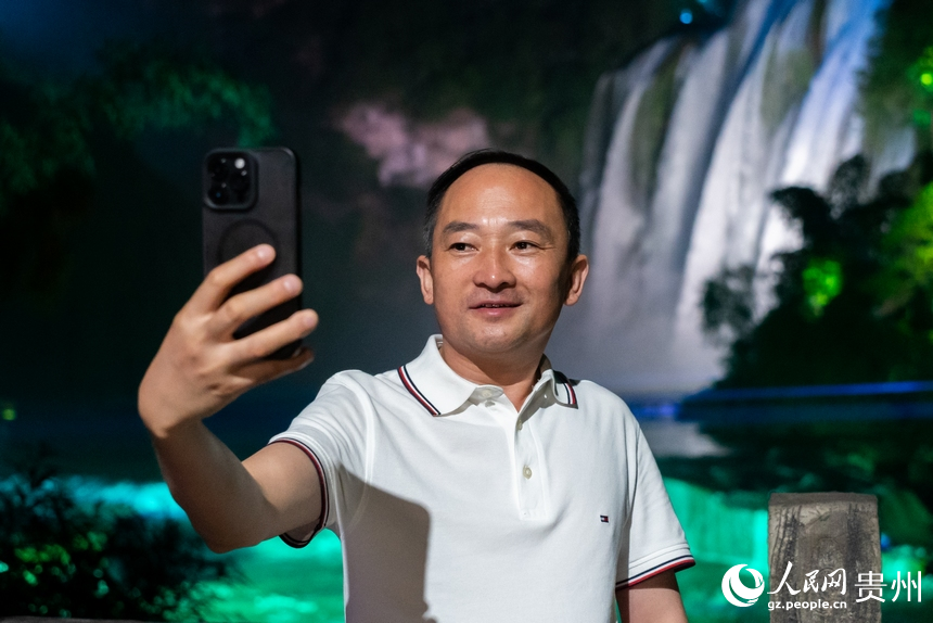 游客在夜間黃果樹瀑布前打卡拍照。人民網記者 涂敏攝