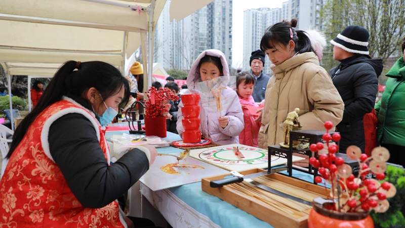 生肖糖畫攤位前，小朋友們排隊買糖。