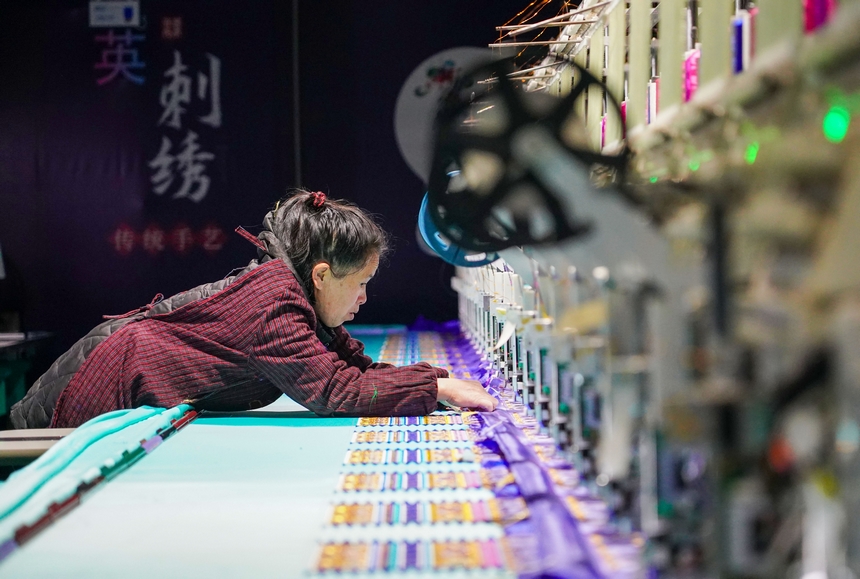 在貴州省從江縣美娥社區一家民族刺繡企業生產車間，工人在用數控機床生產刺繡產品。