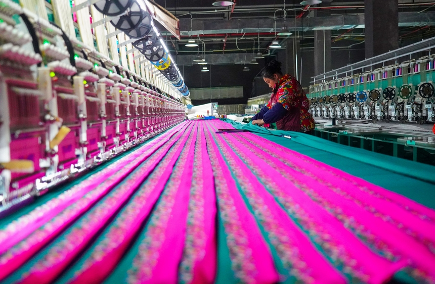 在貴州省從江縣美娥社區一家民族刺繡企業生產車間，工人在用數控機床生產刺繡產品。