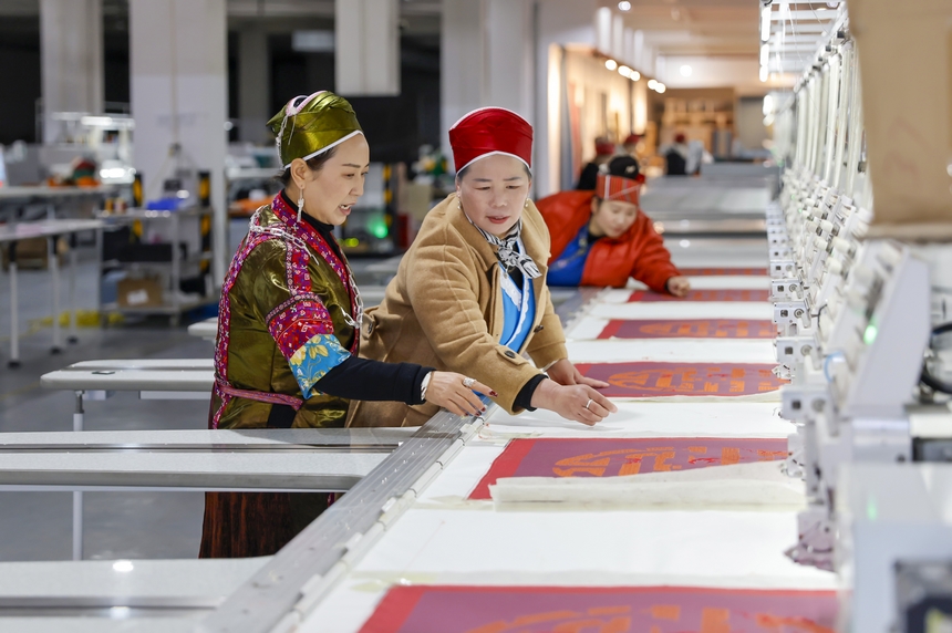 龍祿穎（左）與公司員工在苗繡產品數字化云生產平臺查看苗繡產品。