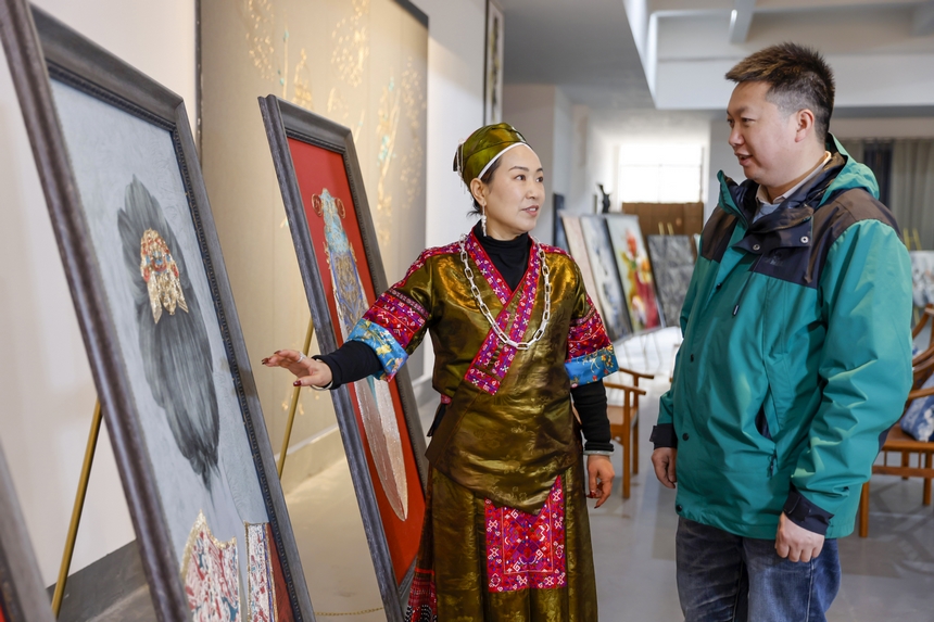 龍祿穎（左）在公司展廳向前來參觀的客人介紹苗繡產品。