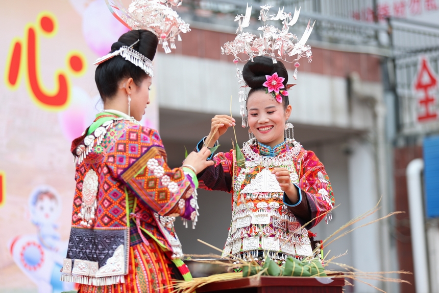 2025年5月29日，在貴州省丹寨縣金泉街道，身著傳統服飾的搬遷群眾在參加包粽子比賽。