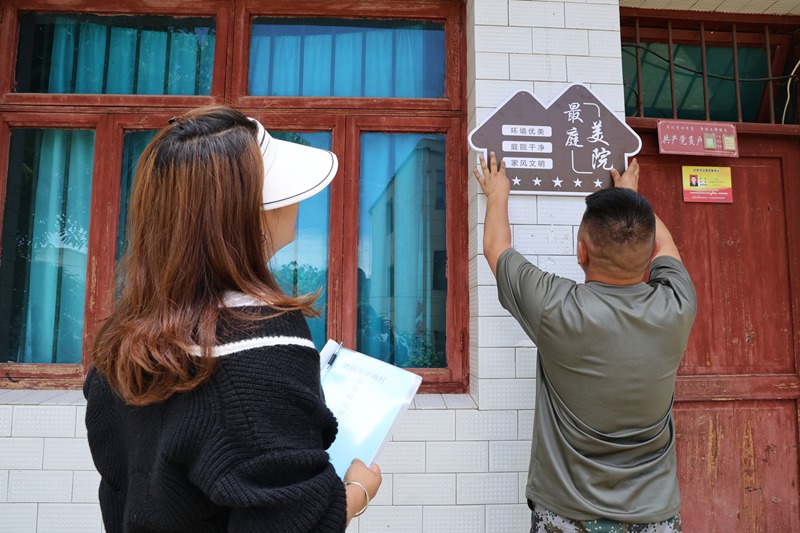 歹雞村村干部為村民張貼最美庭院牌子。