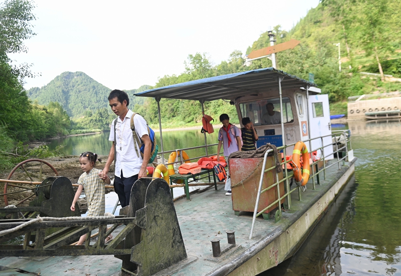 松桃苗族自治縣迓駕鎮教師任達兵帶著學生乘坐渡船回家。謝慧芳攝.JPG