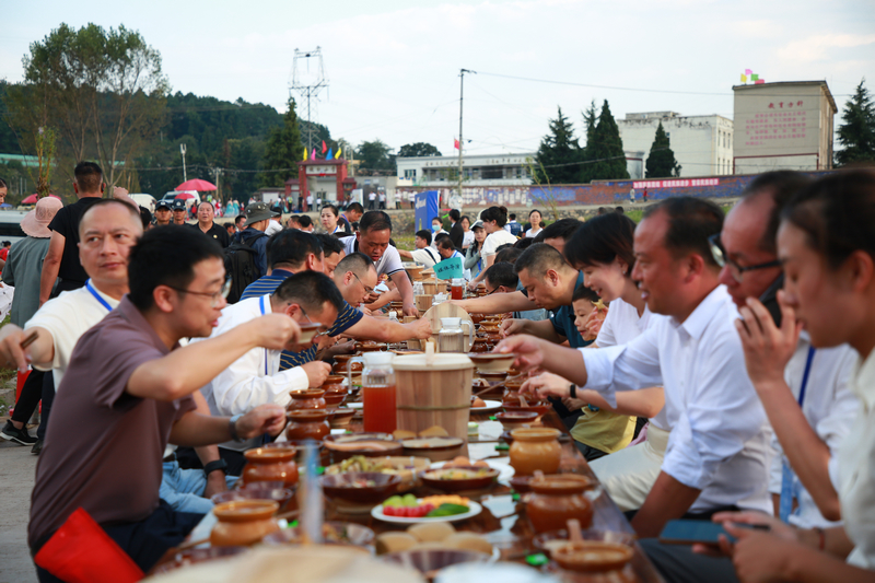 七星關區2025年中國農民豐收節分會場活動現場， 稻田長桌宴 游客與村民共品菜肴，共話豐收年景。