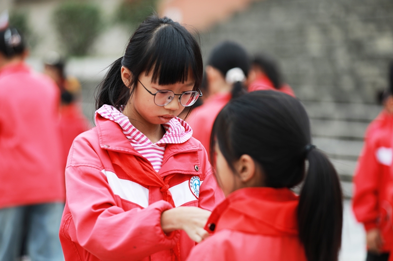 2025年10月13日，貴州省黔西市林泉鎮林泉小學高年級的少先隊員在為一年級的少先隊員佩戴紅領巾。