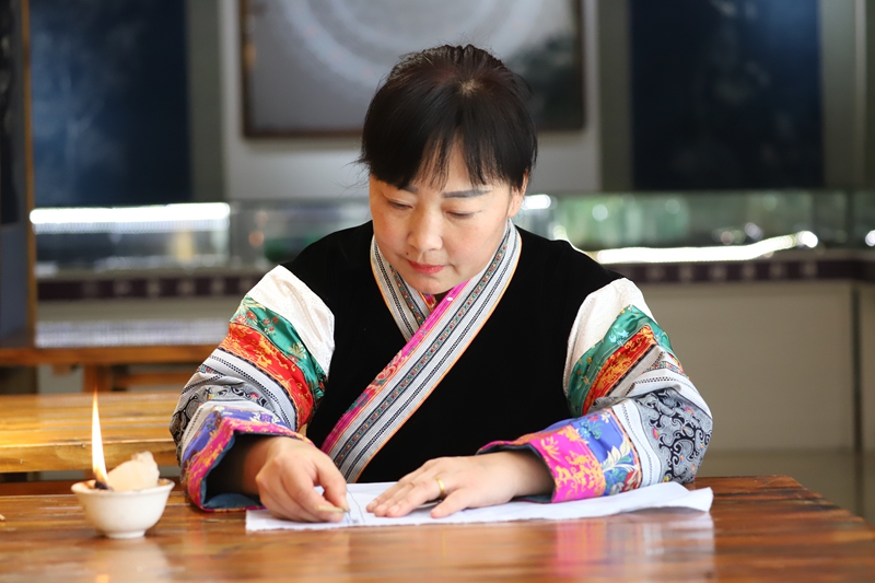 織金縣蔡群苗族蠟染刺繡有限公司總經理蔡群用蠟刀在畫布上勾勒圖案（孫繼霞 攝）